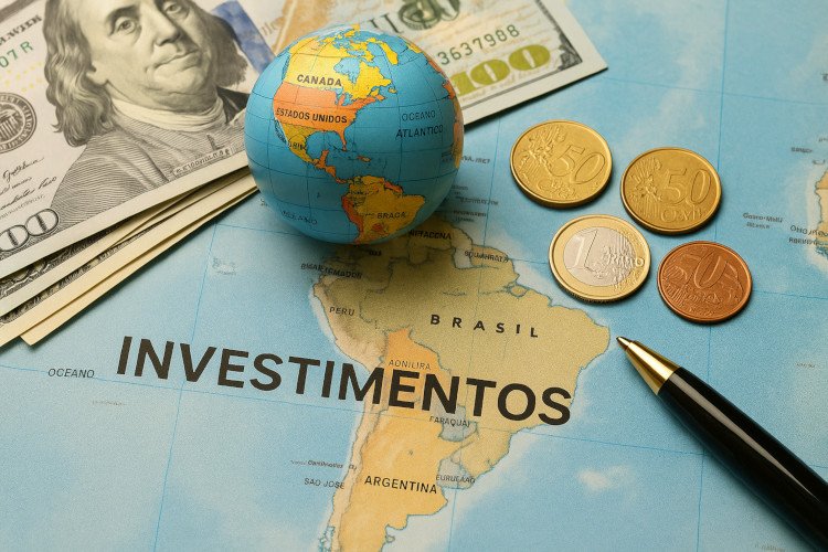 Investir no exterior representado por moedas estrangeiras, dólar, globo terrestre e mapa do Brasil